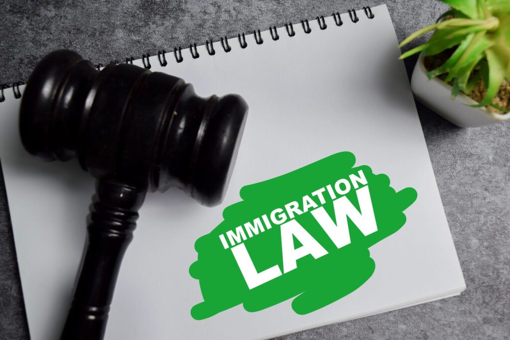 Concept of immigration law write on book with gavel isolated on Wooden Table.